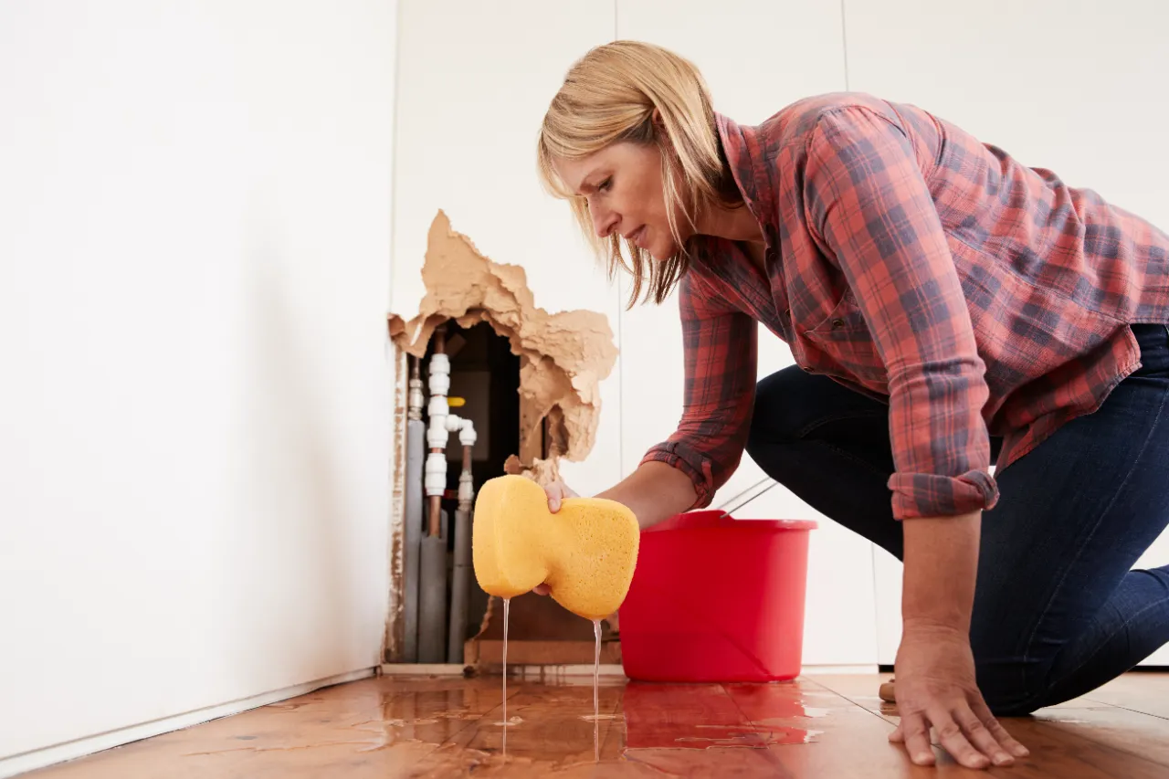 Woman dealing with water from burst pipe emergency